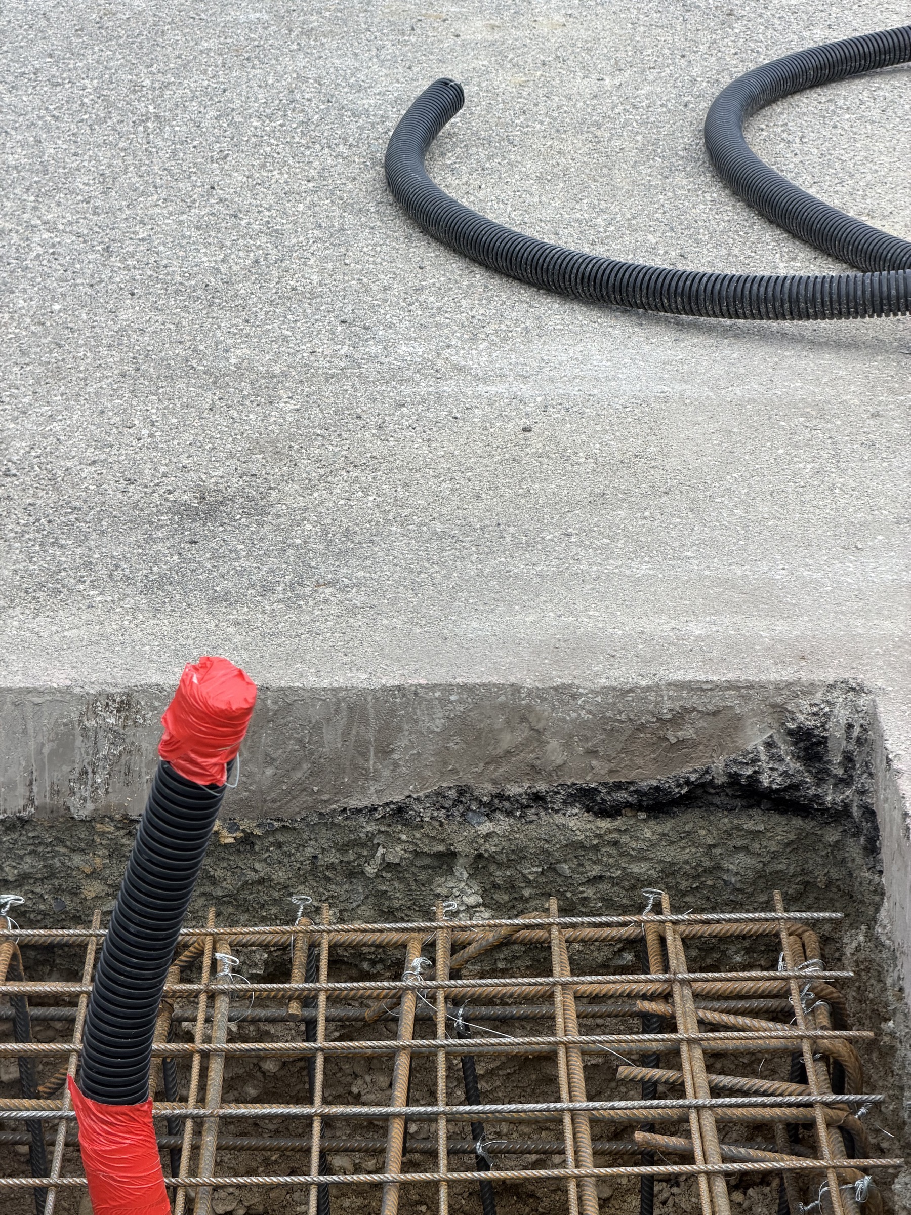Black pipes and a red capped tube on a concrete construction site