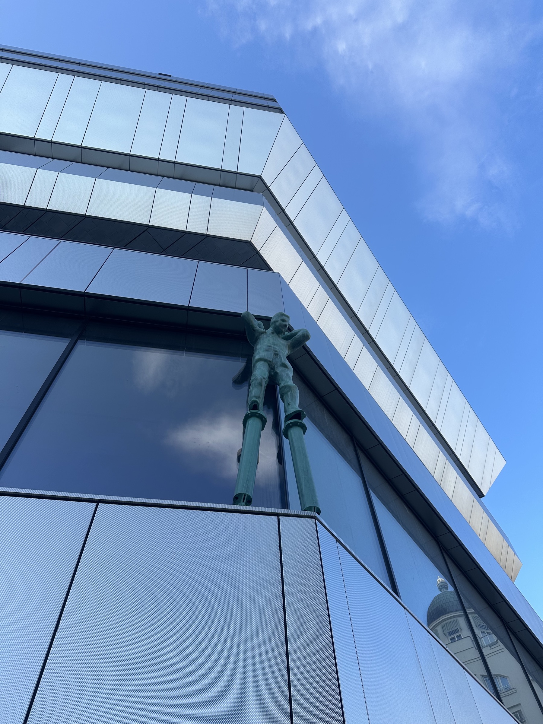 A sculpture in front of a metal clad building and blue sky