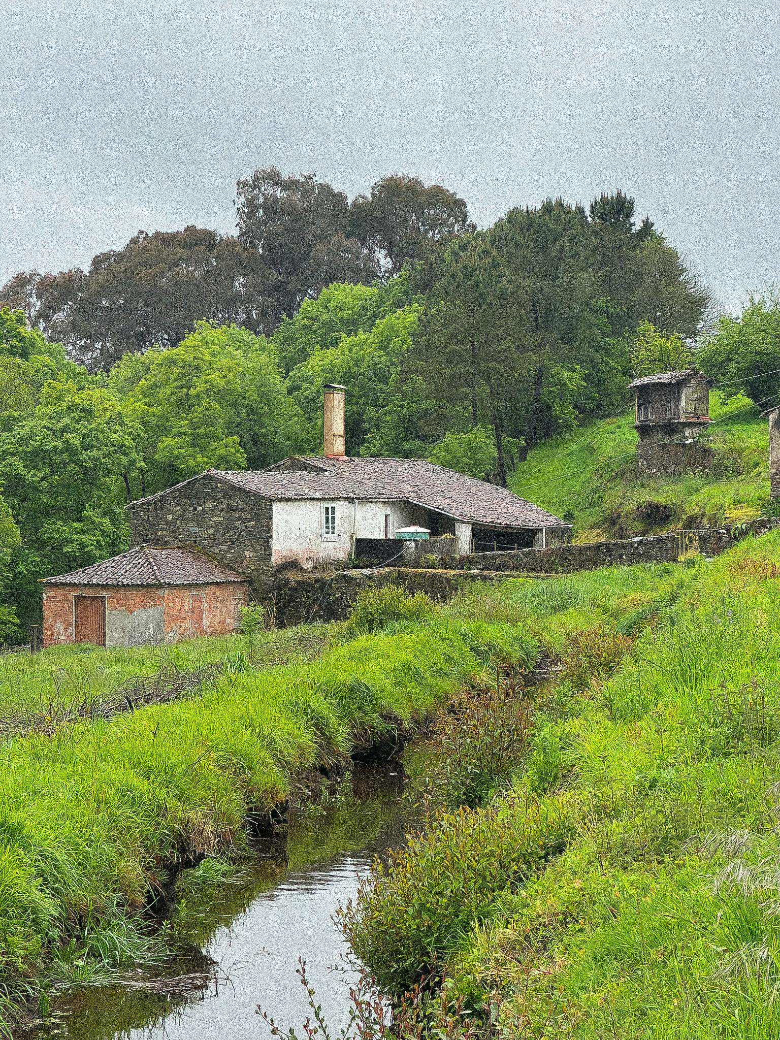A stream beside stone houses and green hills